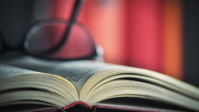 Close up of a pair of glasses on an open book.
