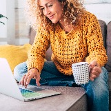 woman-looks-at-laptop-with-coffee-cup
