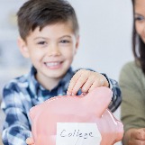 young-boy-puts-money-in-piggy-bank-labeled-college